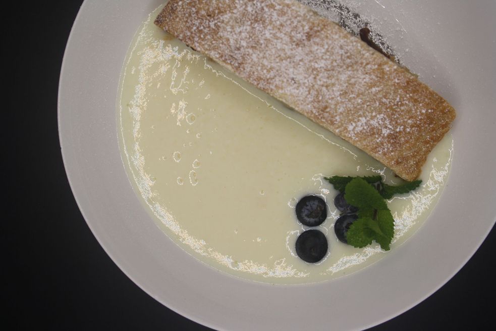 Apfelstrudel mit Vanillesauce in einem tiefen Teller